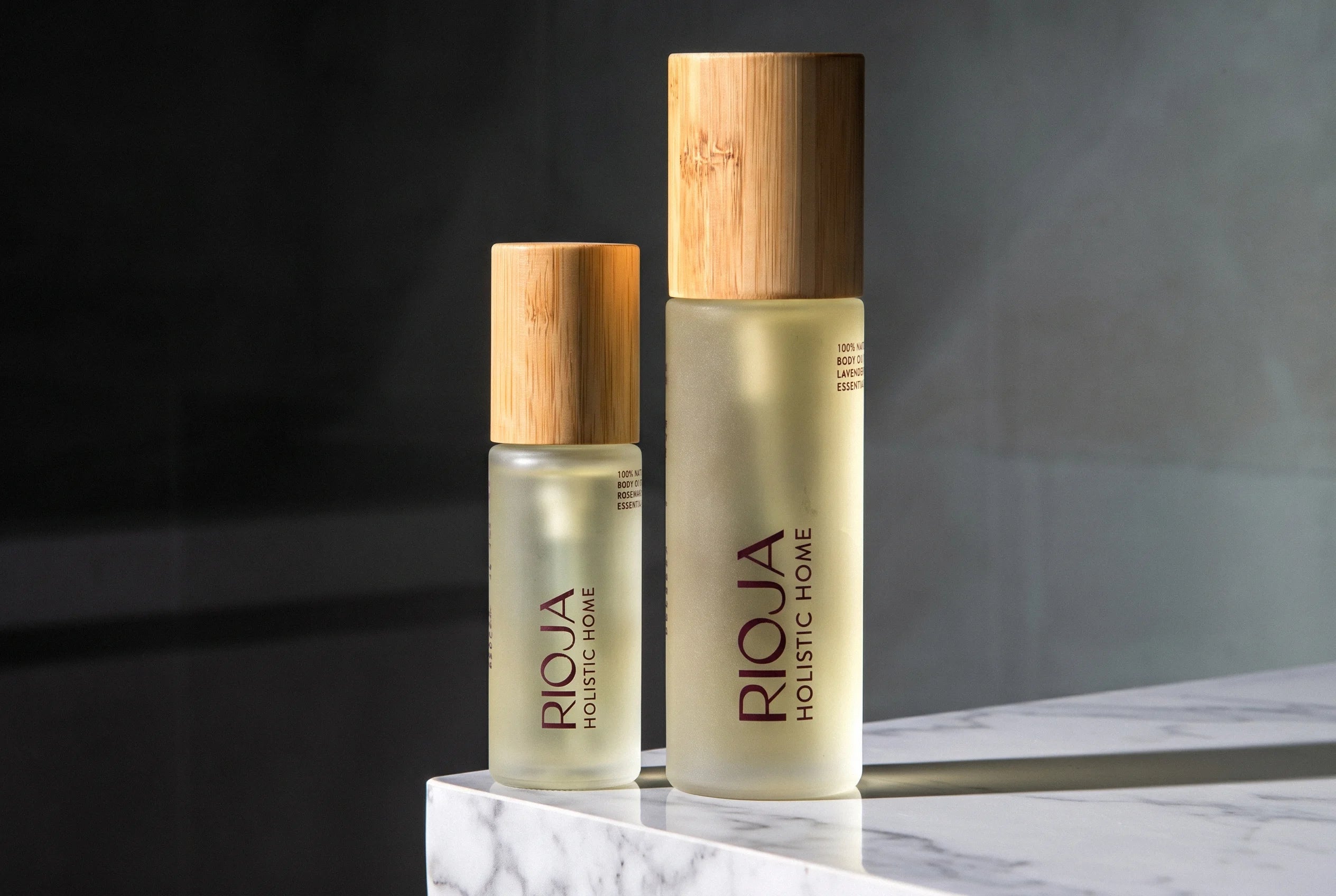 Lavender and Rosemary Body oil bottles with wooden cap on a dark background by Rioja Holistic Home