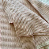 soft pink natural fiber merino wool baby blanket  on a textured surface