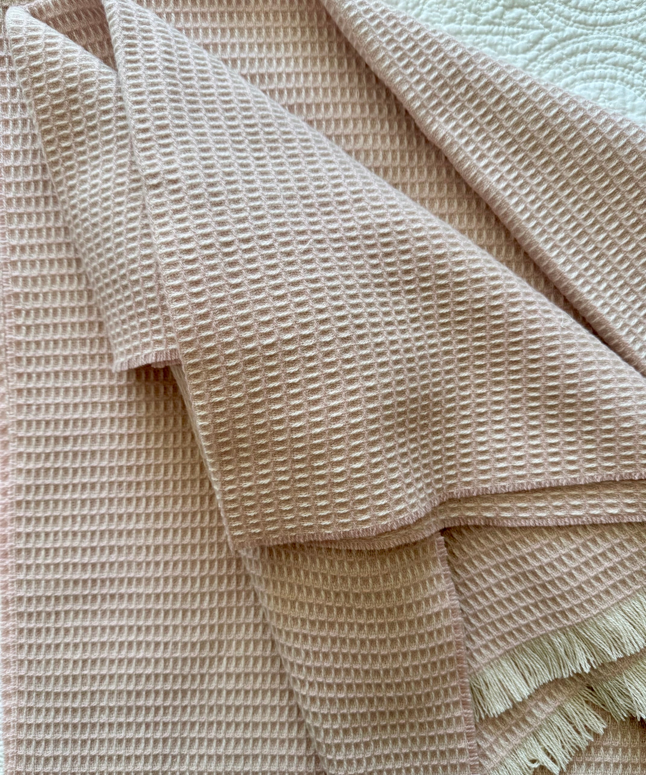 soft pink natural fiber merino wool baby blanket  on a textured surface