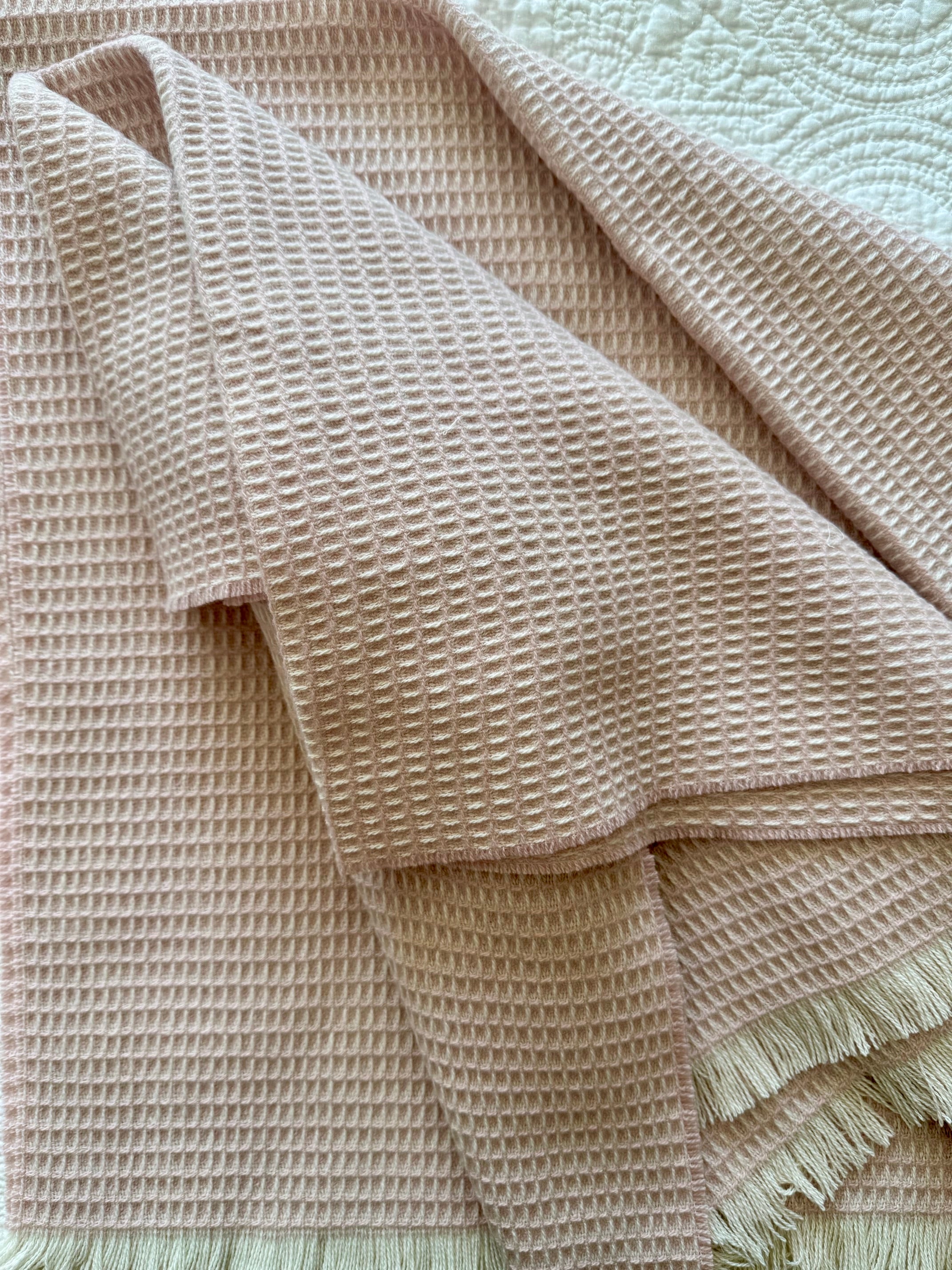 soft pink natural fiber merino wool baby blanket  on a textured surface