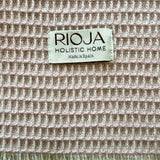 Textile natural fiber with 'Rioja Holistic Home' label on a textured waffle weave fabric background