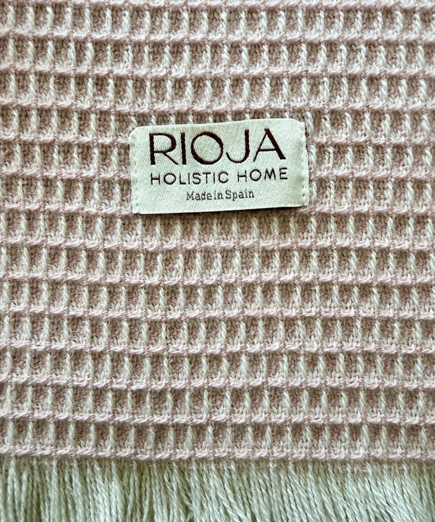 Textile natural fiber with 'Rioja Holistic Home' label on a textured waffle weave fabric background