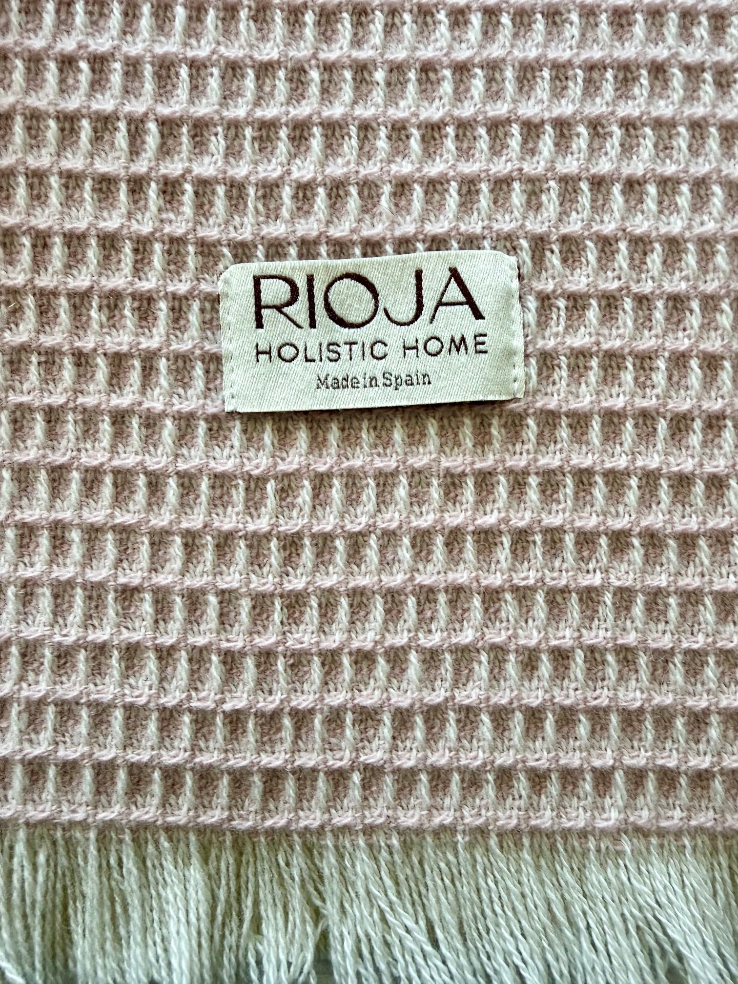 Textile natural fiber with 'Rioja Holistic Home' label on a textured waffle weave fabric background