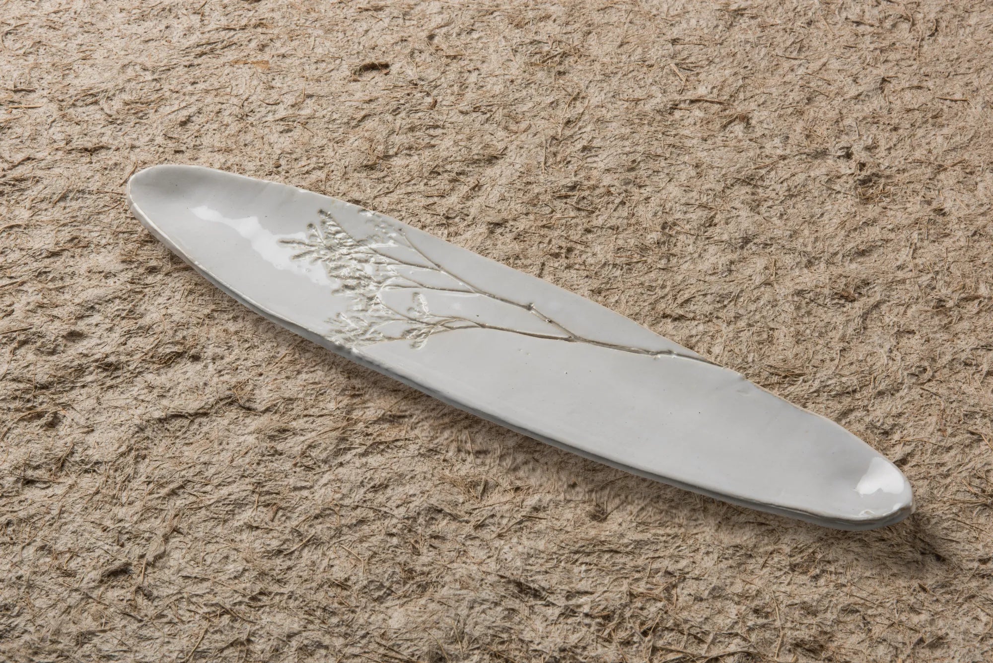 White ceramic Blanco Tray with floral design on a sandy surface