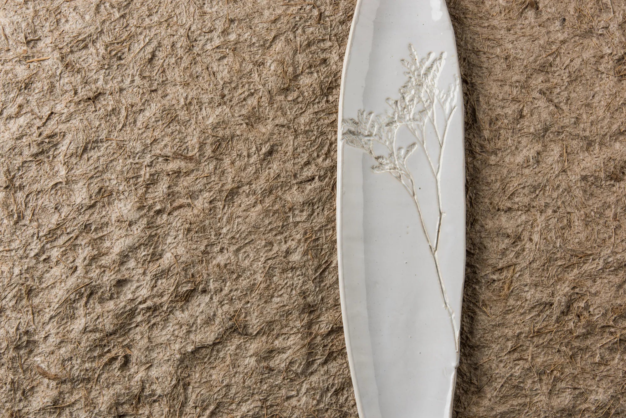 White ceramic Blanko tray with floral design on a brown textured surface