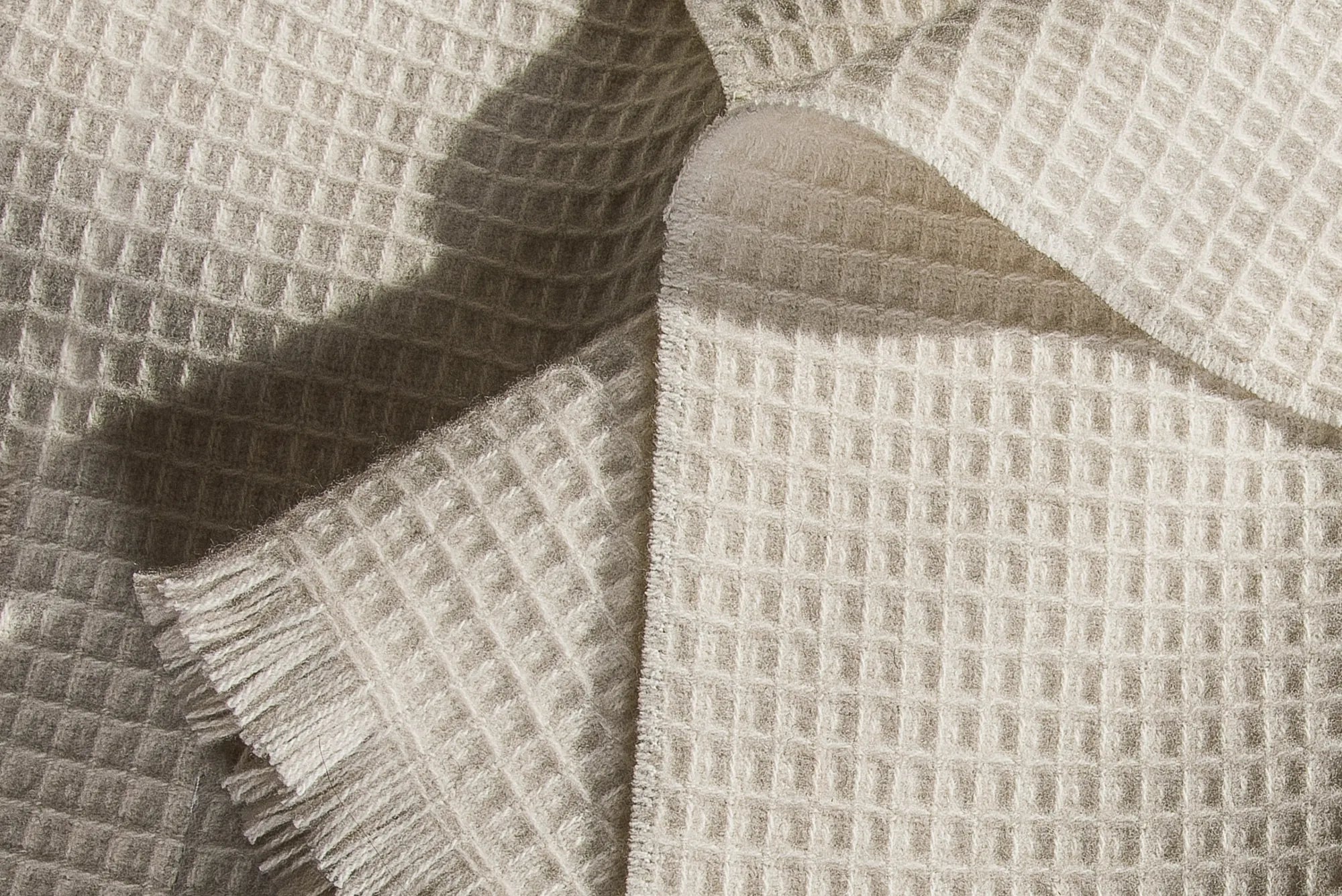 Close-up of textured beige 100% merino wool baby blanket with a waffle pattern