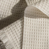 Close-up of textured beige 100% merino wool baby blanket with a waffle pattern