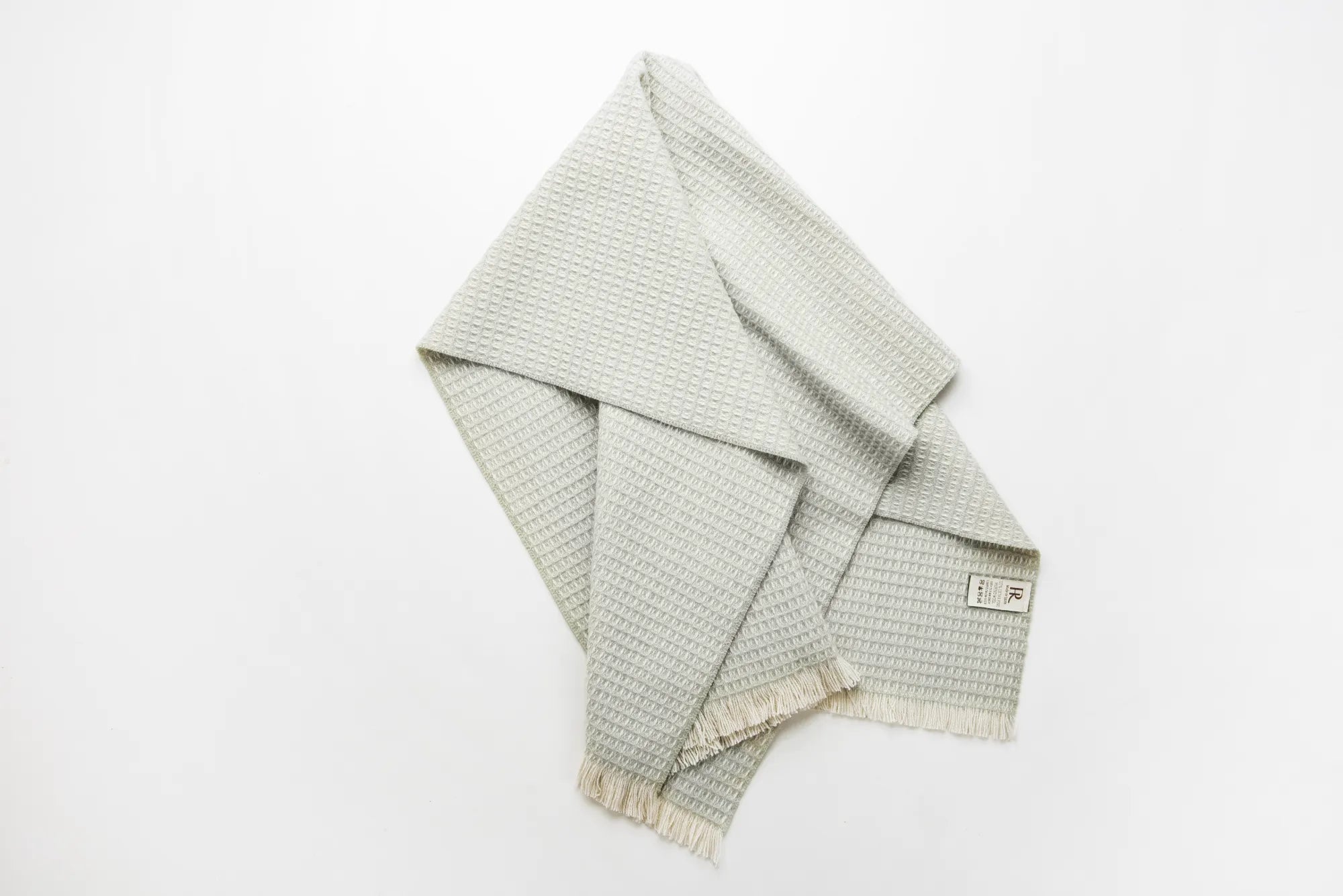 Folded sage checkered 100% merino wool baby blanket on a white background