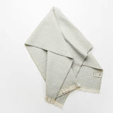 Folded sage checkered 100% merino wool baby blanket on a white background