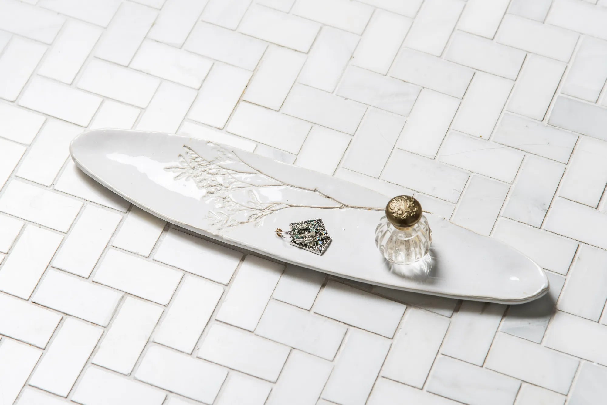 Decorative white plate with a small Blanko tray and decorative elements on a tiled surface