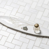 Decorative white plate with a small Blanko tray and decorative elements on a tiled surface