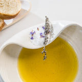 Ceramic Cuenko bowl of olive oil with a lavender sprig, bread slices on a white plate.