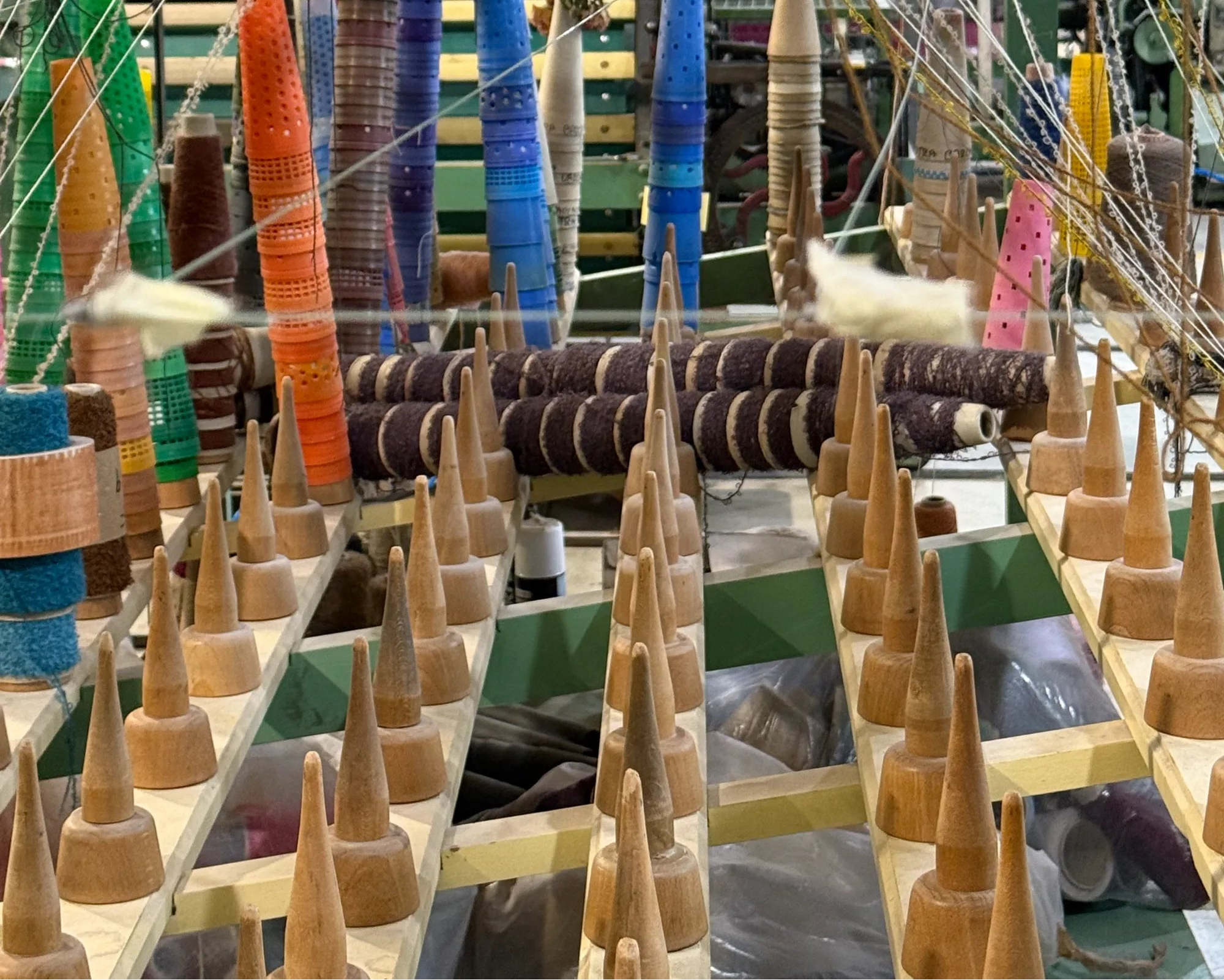 Spinning bobbins on a textile machine with colorful wool yarn.