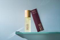 Rioja body oil bottle and box on a glass shelf against a light blue background