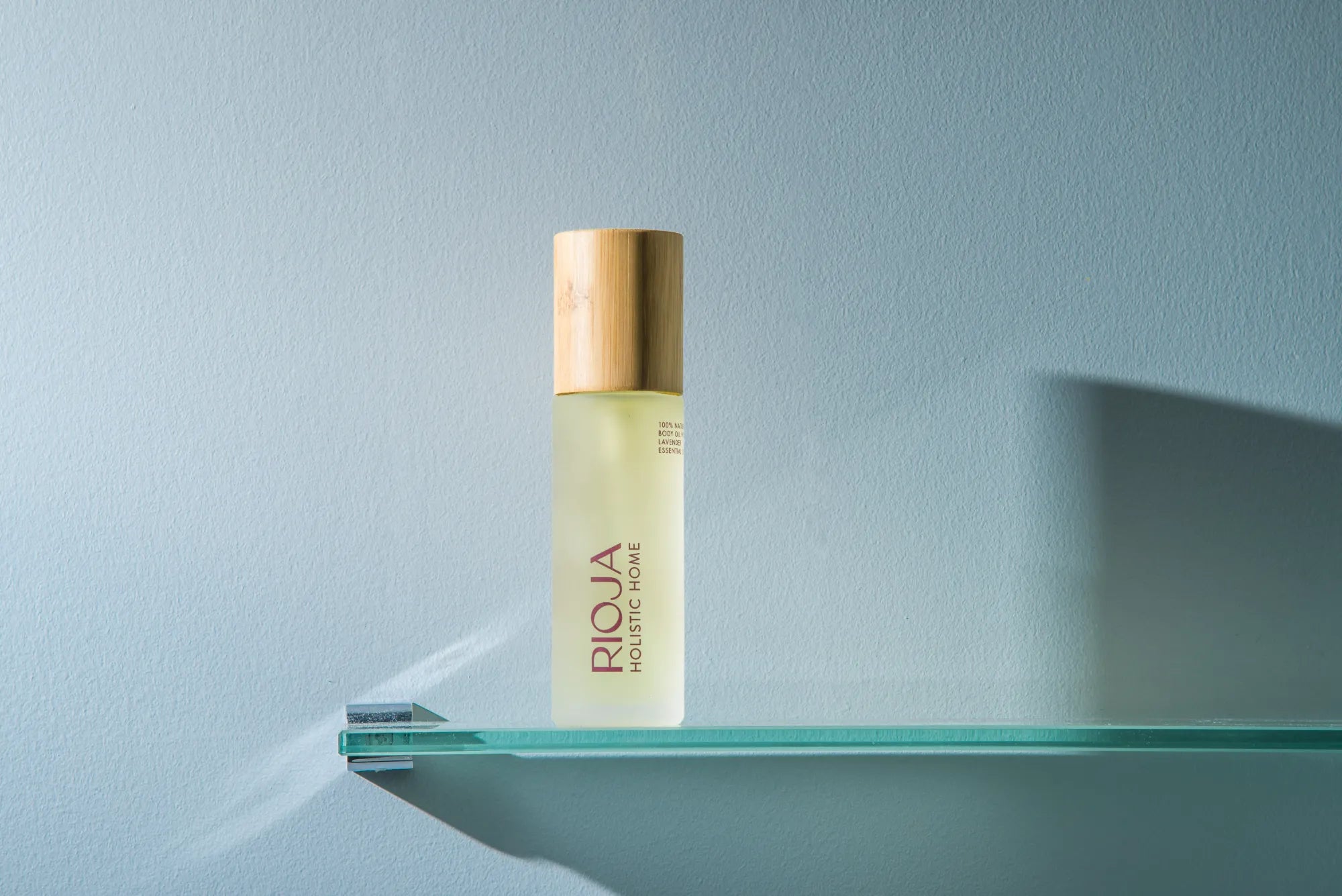 Rioja Holistic Home body oil labeled on a glass shelf with a light blue background