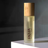 Body oil bottle with wooden cap on a dark background by Rioja Holistic Home