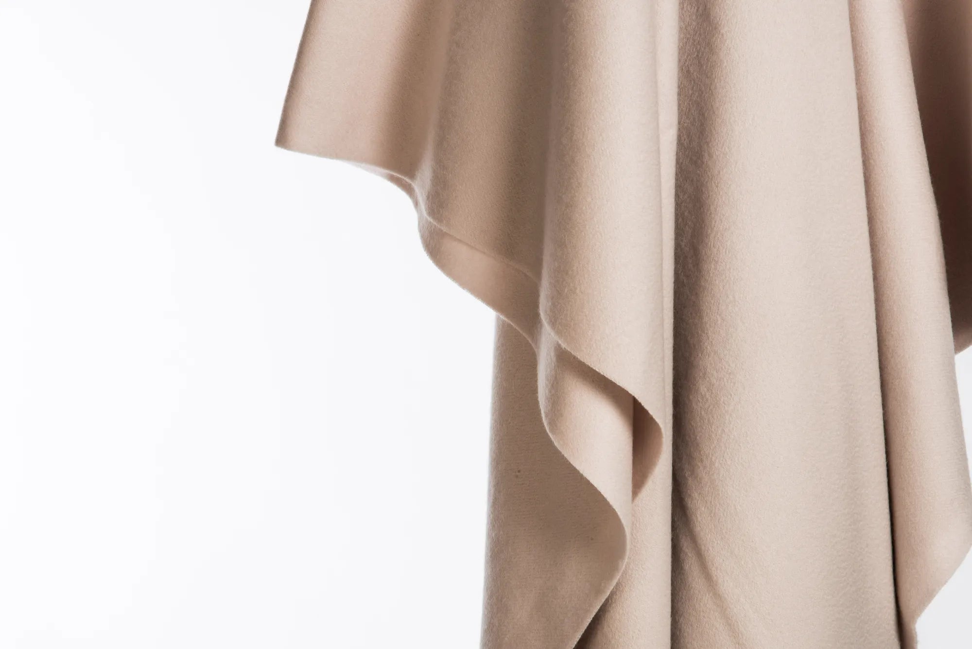 Beige 100% merino wool blanket draped over a white surface