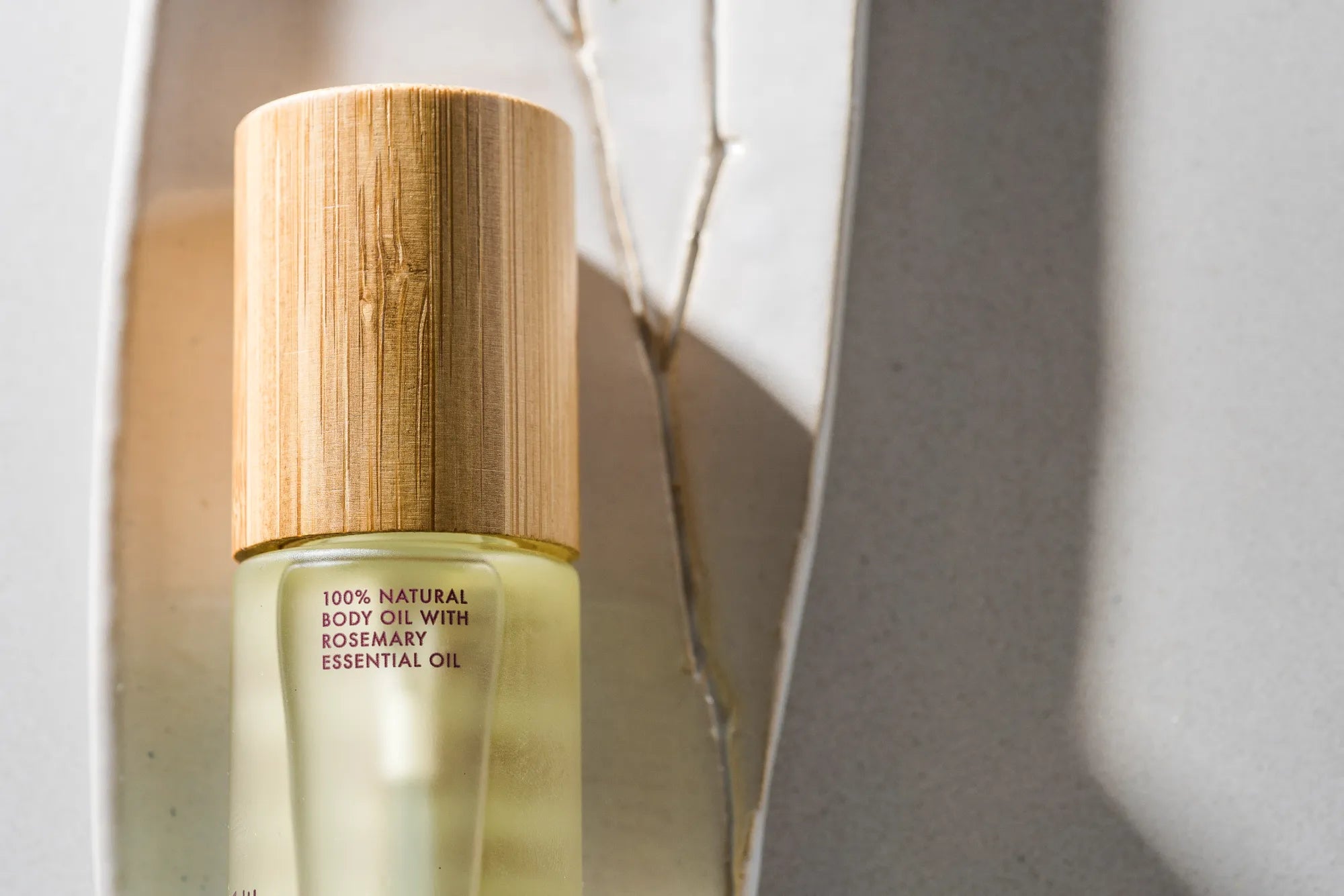 Bottle of natural body oil with a wooden cap on a light background