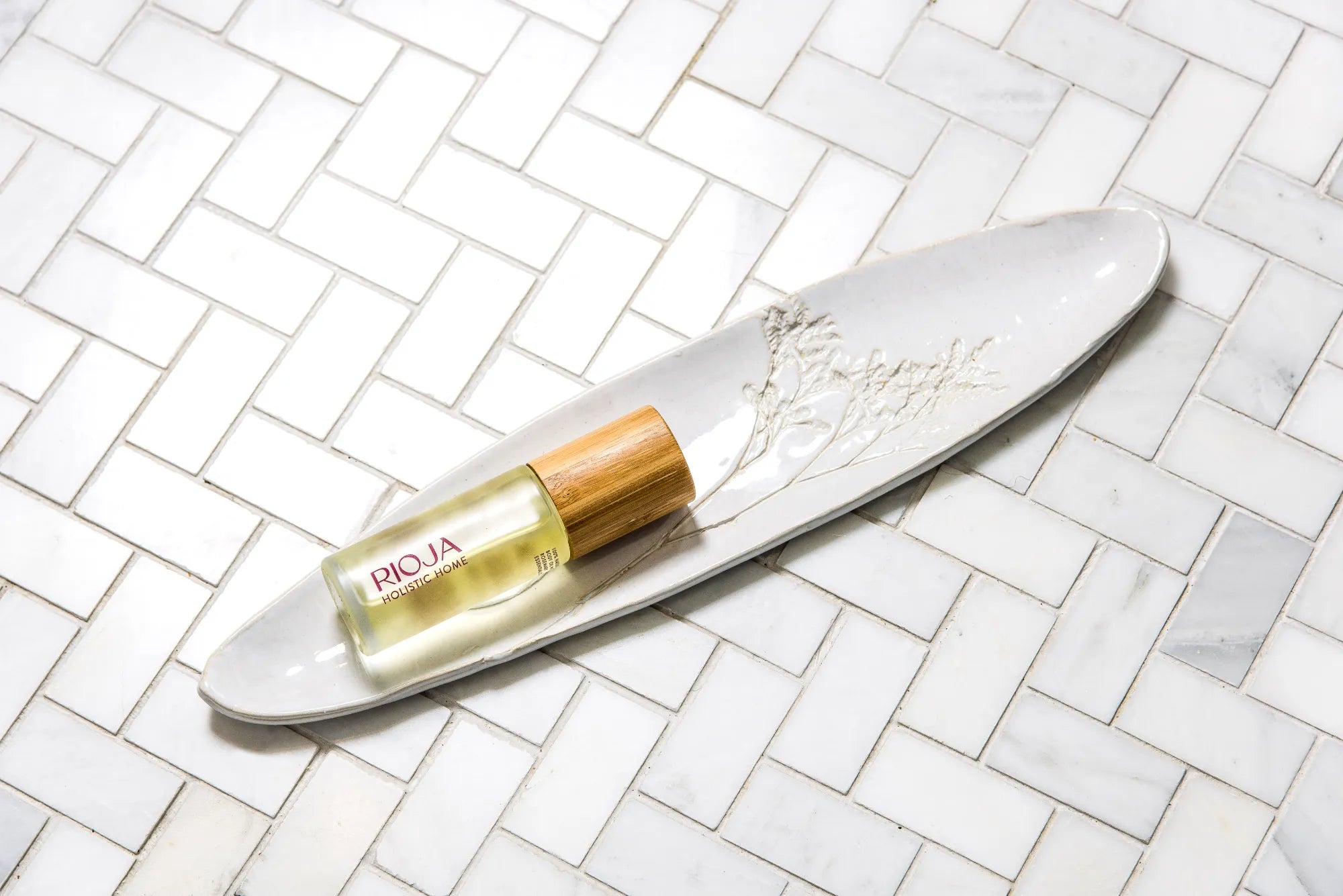 Rioja Holistic Home body oil product on a white dish with a tiled background
