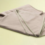 Folded beige 100% merino wool blanket on a light green background