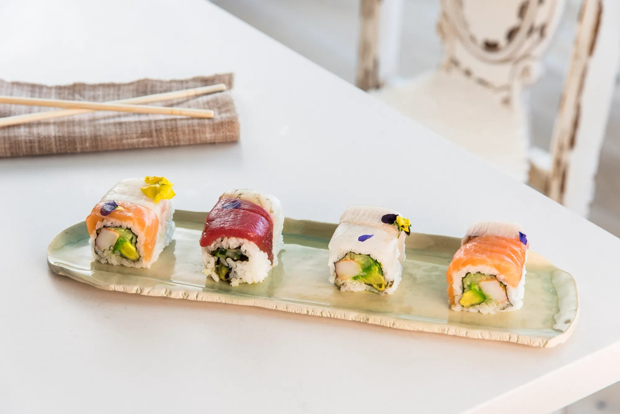 Four pieces of sushi on a ceramic Verde Tray with chopsticks and a folded napkin in the background.
