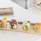Four pieces of sushi on a ceramic Verde Tray with chopsticks and a folded napkin in the background.